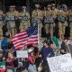 Demonstrators holding signs and flags face California National Guard members standing guard outside the Federal Building