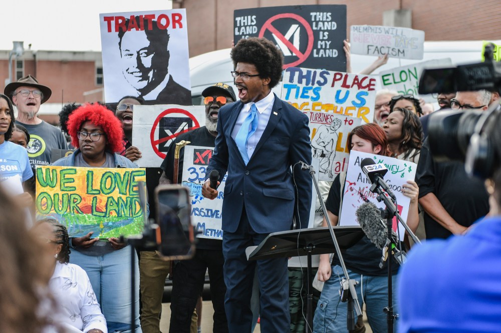 Justin Pearson speaks in the middle of a crowd holding signs against Elon Musk's xAI facility
