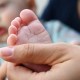 A hand holds a baby's foot