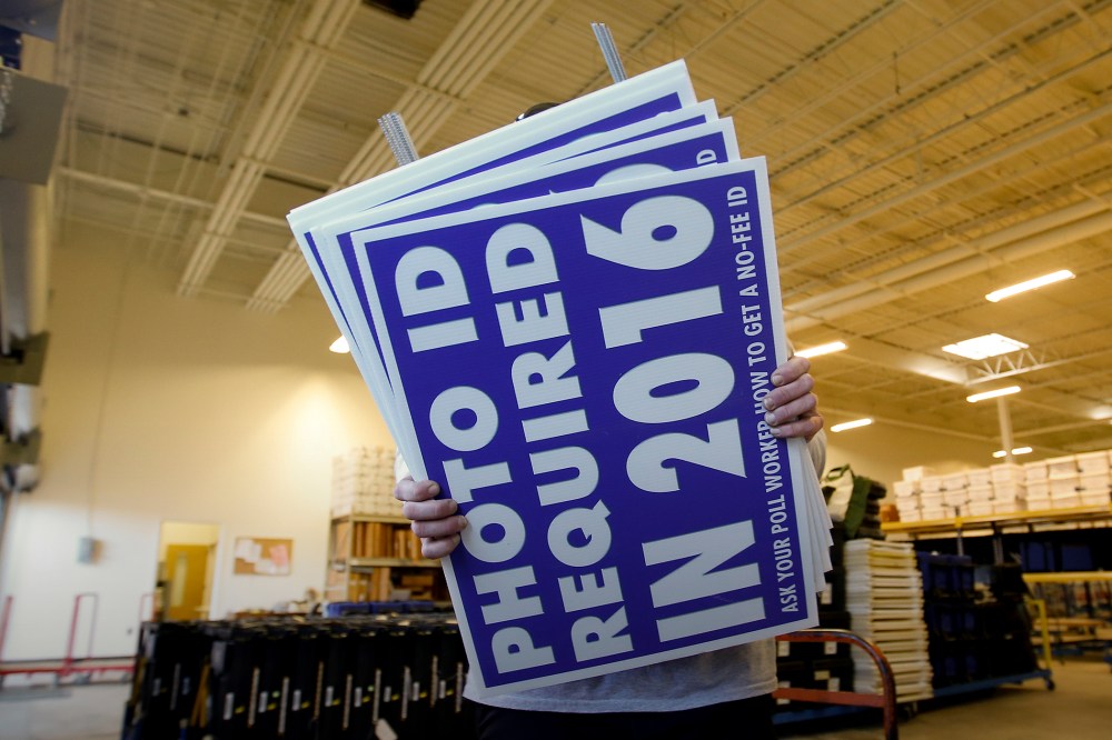 A worker carries signs about a voter ID law that went into effect in 2016 at the Mecklenburg County Board of Elections warehouse in Charlotte, N.C., Nov. 3, 2014. (Photo by Chris Keane/Reuters/Corbis)