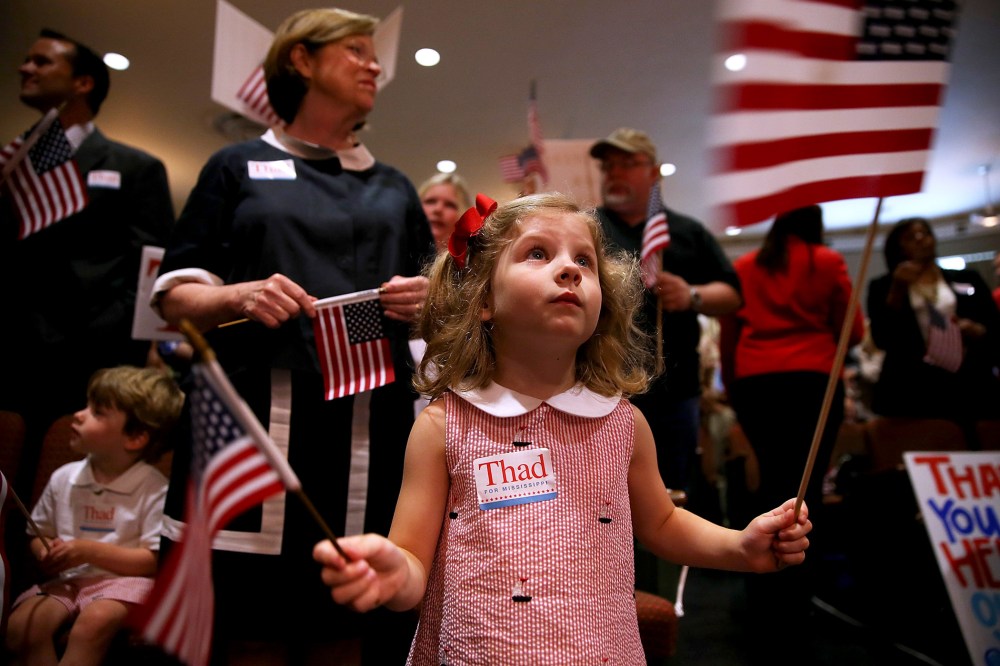 A young supporter of U.S. Sen Thad Cochran (R-MS) waves American flags during a campaign rally on June 23, 2014 in Jackson, Mississippi.