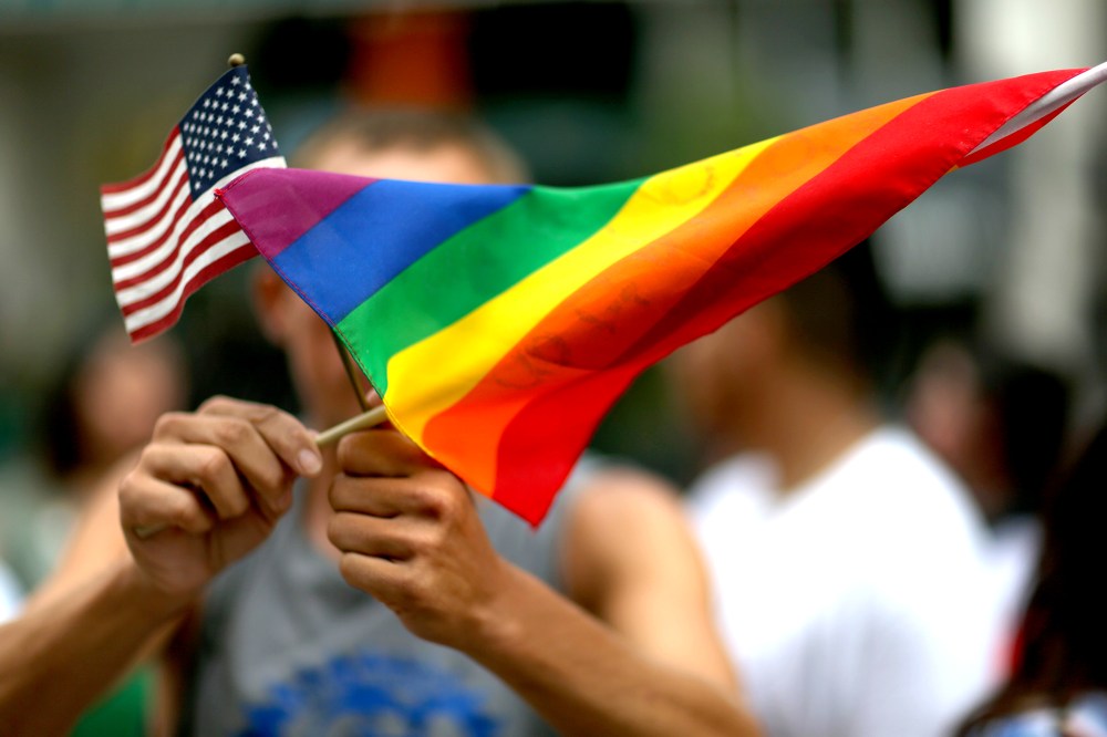 A protester holds an American flag and a rainbow flag.