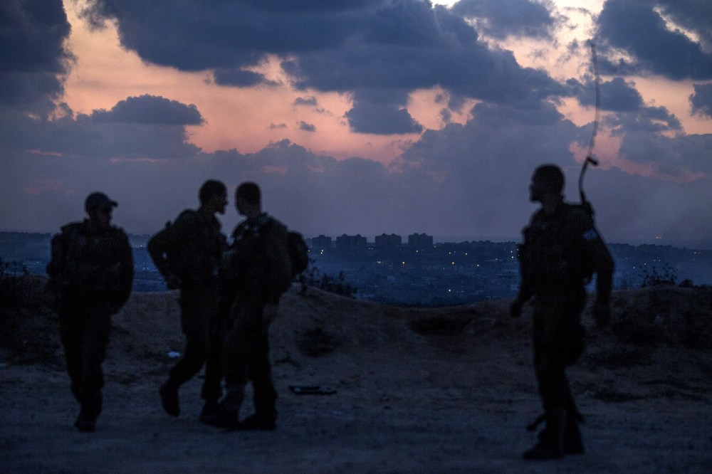 Israeli soldiers stand near the southern Israeli border with the Gaza Strip (background) on July 17, 2014.