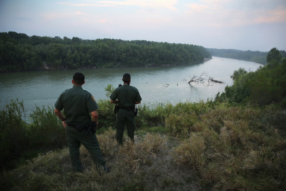 U.S. Border Patrol agents look for immigrants crossing the Rio Grande from Mexico (L), to the United States at dusk on July 24, 2014 near Mission, Texas.