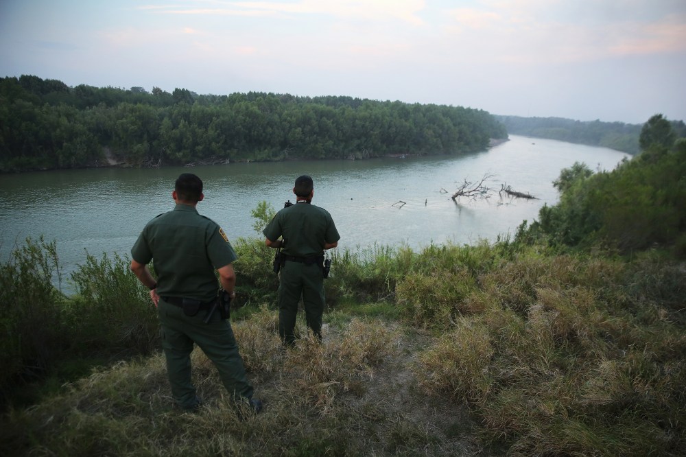 U.S. Border Patrol agents look for immigrants crossing the Rio Grande from Mexico (L), to the United States at dusk on July 24, 2014 near Mission, Texas. (Photo by John Moore/Getty)