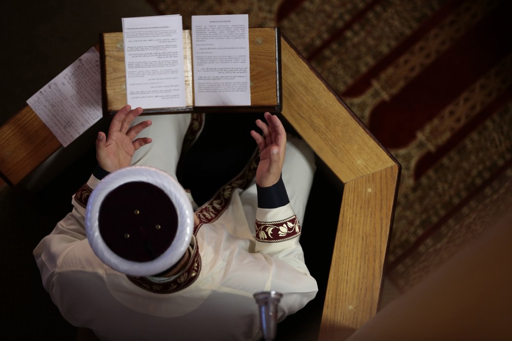A Muslim religious leader reads Quran as Muslims perform Eid al-Fitr prayer in New York on July 28,2014. (Photo by Bilgin Sasmaz/Anadolu Agency/Getty)