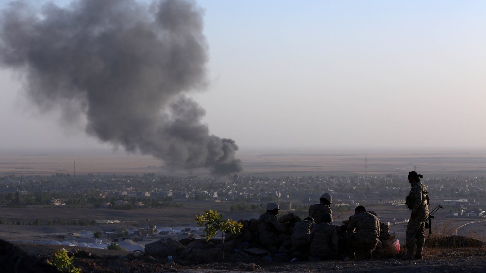 Iraqi Kurdish Peshmerga fighters look on as smoke billows from the town Makhmur, about 280 kilometres (175 miles) north of the capital Baghdad, during clashes with Islamic State (IS) militants on Aug. 9, 2014.