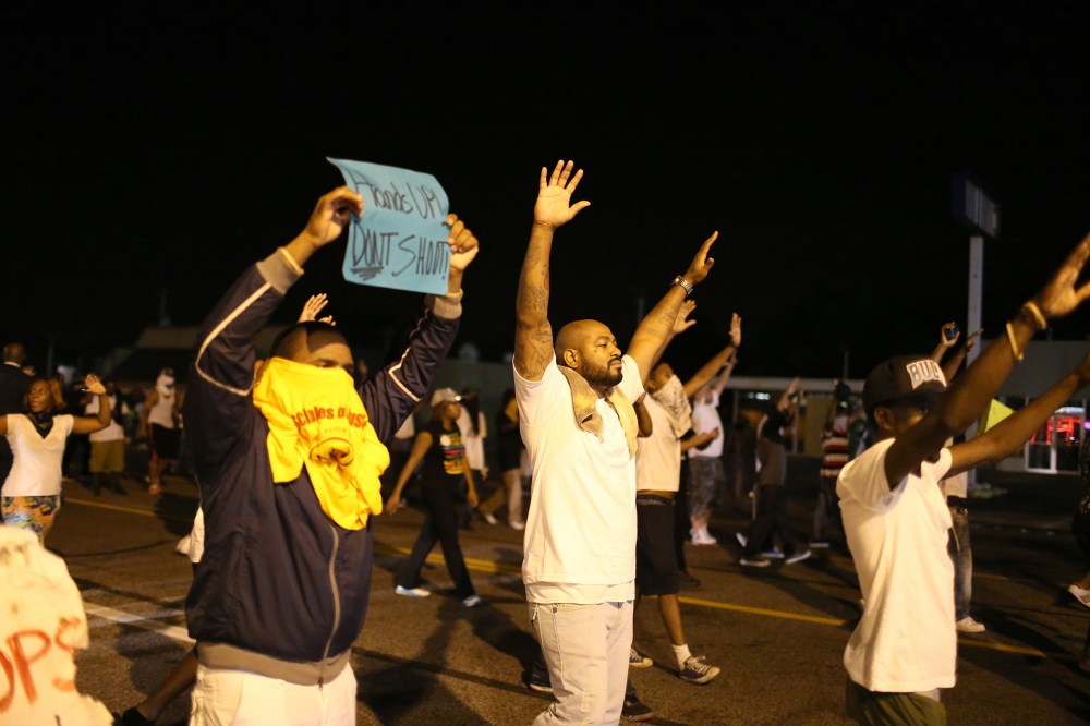 Demonstrators raise their arms and chant, "Hands up, Don't Shoot", as police clear them from the street as they protest the shooting death of Michael Brown on Aug. 17, 2014 in Ferguson, Mo.