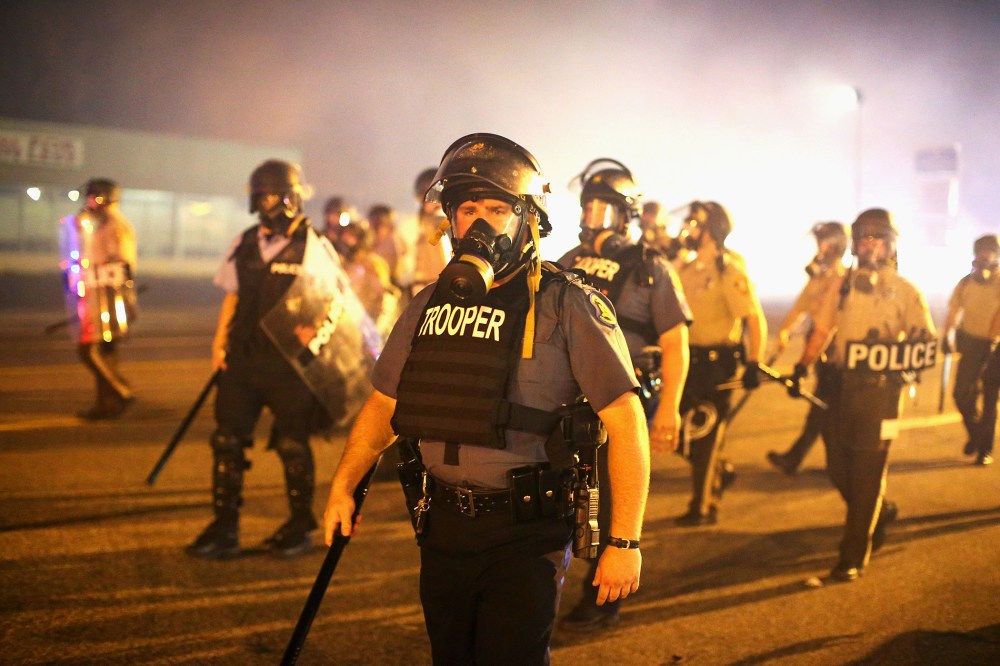 Police advance through a cloud of tear gas toward demonstrators protesting the killing of teenager Michael Brown on Aug. 17, 2014 in Ferguson, Mo.