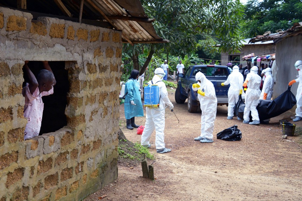 A neighbor of an Ebola virus victim looks at medical workers of the Liberian Red Cross carry his body on Sept. 4, 2014 in the small city of Banjol, 30 kilometres of Monrovia, Libera.