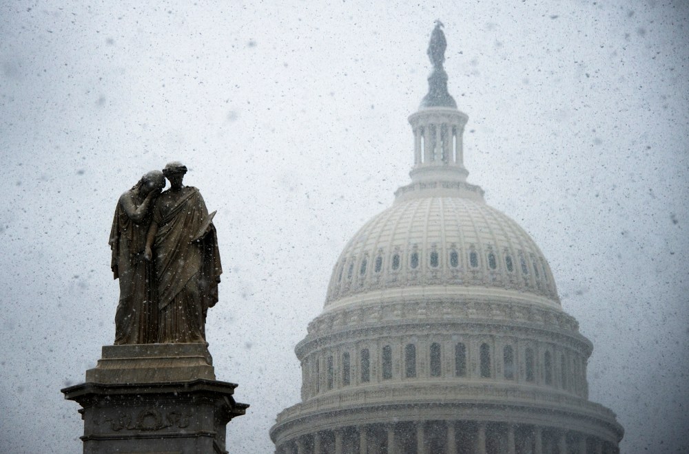 Snow begins to gather on a statue outside the US Capitol Building in Washington, DC, Dec.10, 2013.
