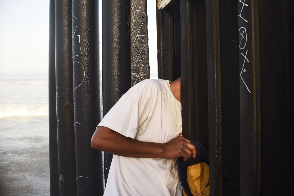 A man looks through the fence that divides Mexico and the US, in Tijuana, Baja California State, Mexico, on September 17, 2014.