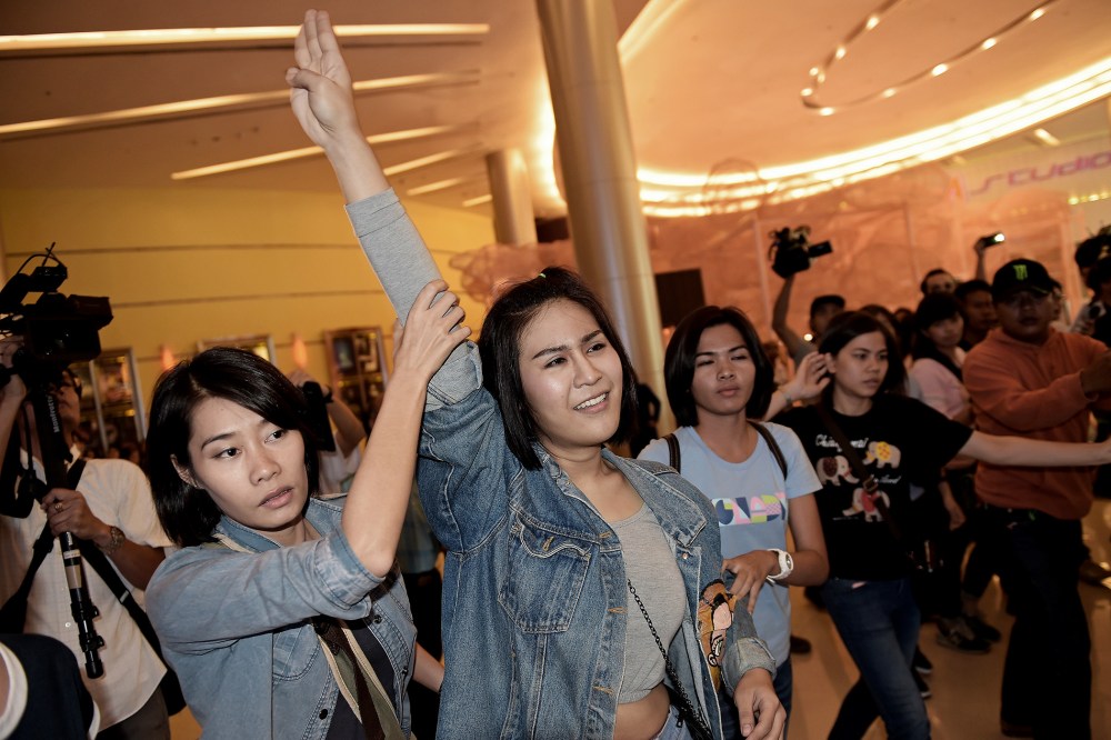 A Thai student flashes a three-finger salute as she is escorted out of a cinema hall by plainclothes female police officers in Bangkok on Nov. 20, 2014.