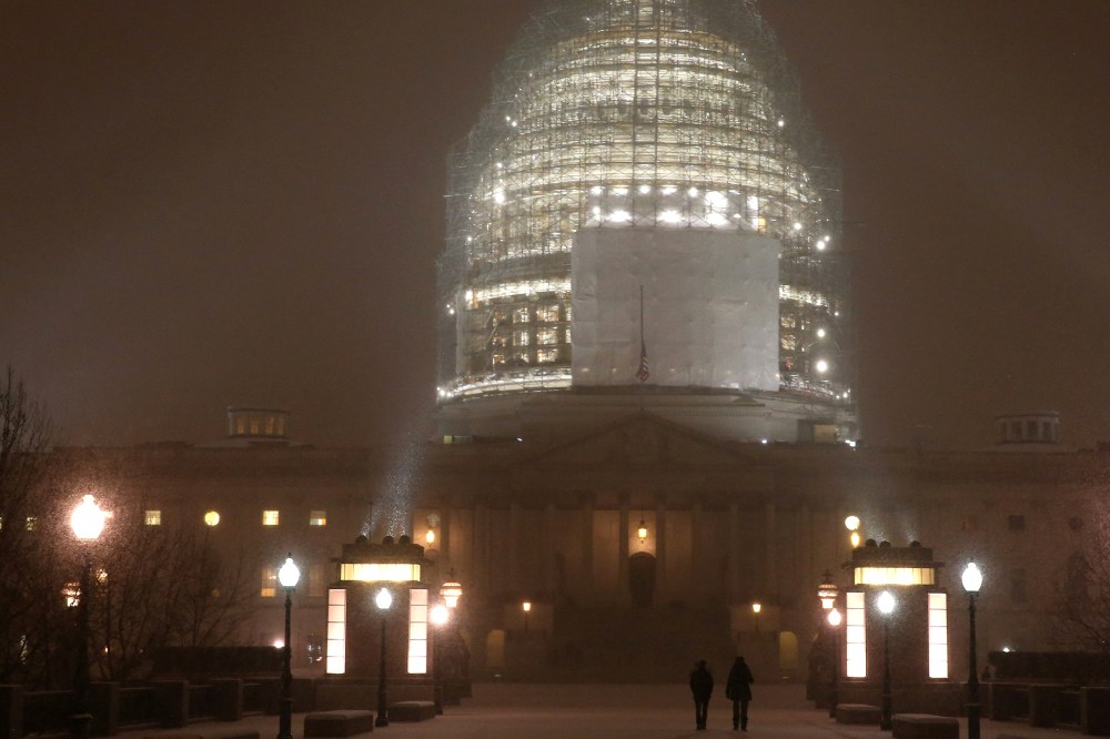 People walk in the falling snow in front of the US Capitol, on Jan. 6, 2015 in Washington, DC.