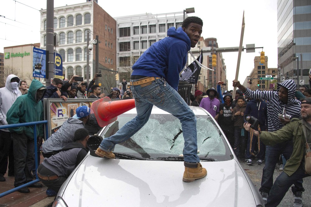 Demonstrators destroy the windshield of a Baltimore Police car as they protest the death Freddie Gray, an African American man who died of spinal cord injuries in police custody, in Baltimore, Md., April 25, 2015. (Photo by Jim Watson/AFP/Getty)