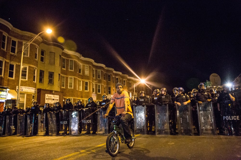 A protester sits in front of riot police minutes before a mandatory, city-wide curfew of 10 p.m. near the CVS pharmacy that was set on fire yesterday during rioting after the funeral of Freddie Gray, on April 28, 2015 in Baltimore, Md.