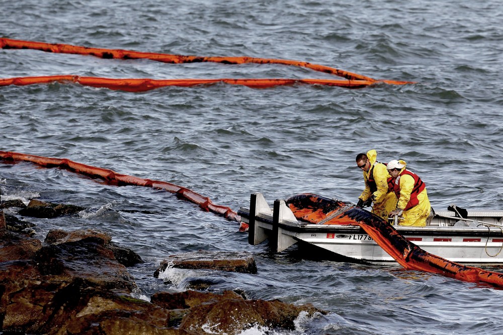 People with Garner Environmental Services work with oil booms that line the coast of East Beach on the Houston Ship Channel on March 25, 2014 in Galveston, Texas.