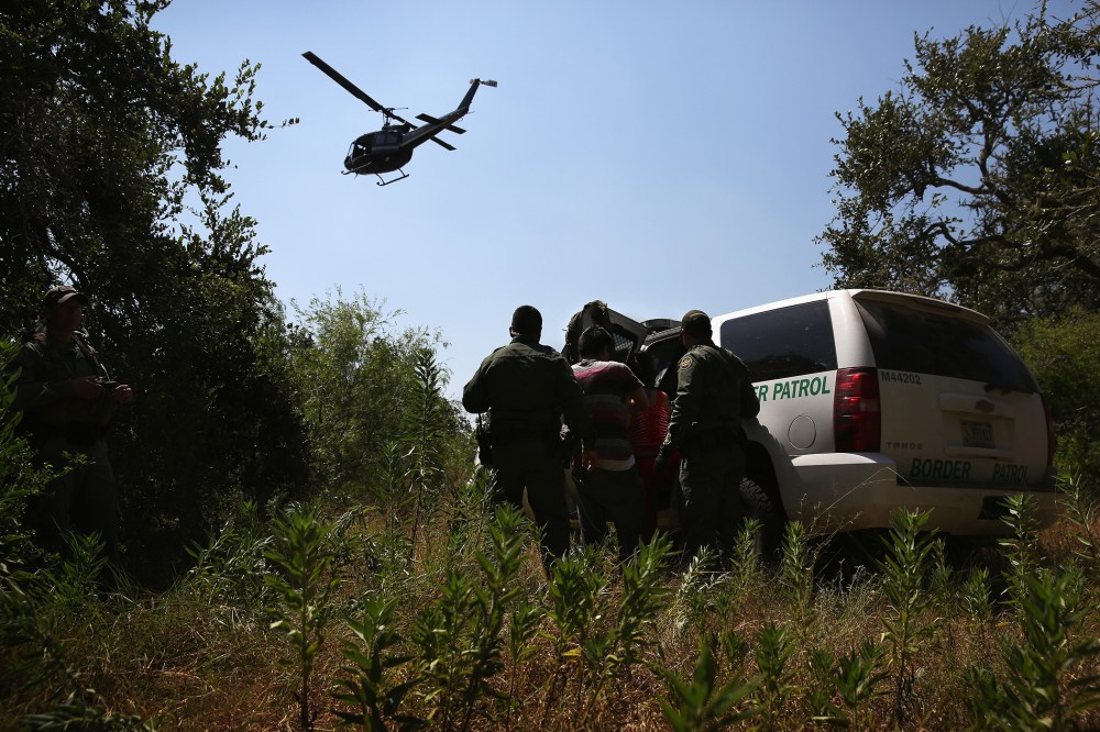 U.S. Border Patrol agents detain undocumented immigrants with the help of helicopter support from the U.S. Office of Air and Marine north of the U.S.-Mexico border on Aug. 6, 2015 near Falfurrias, Texas. (Photo by John Moore/Getty)