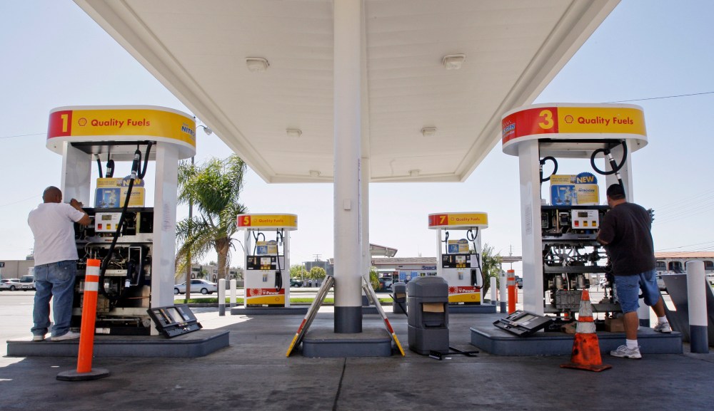 David Berri, right, and his assistant Adolfo Mendez install new valves and electronic controls to a pair of gas pumps at the Shell station Berri owns in Santa Ana, Calif., Saturday, March 28, 2009.  (AP Photo/Reed Saxon)