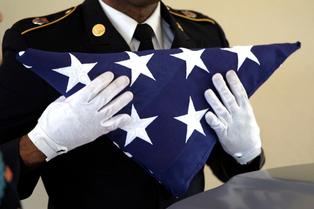 An Army National Guardsman, holds an American flag during a funeral.