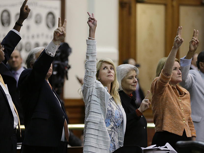 Sen. Wendy Davis, D-Fort Worth, center, holds up two fingers to signal a no vote as the session where they tried to filibuster an abortion bill draws to a close, Tuesday, June 25, 2013, in Austin, Texas. (Photo by Eric Gay/AP)
