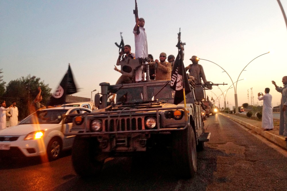 In this June 23, 2014 photo, fighters from the Islamic State group parade in a commandeered Iraqi security forces armored vehicle down a main road at the northern city of Mosul, Iraq. (Photo by AP)