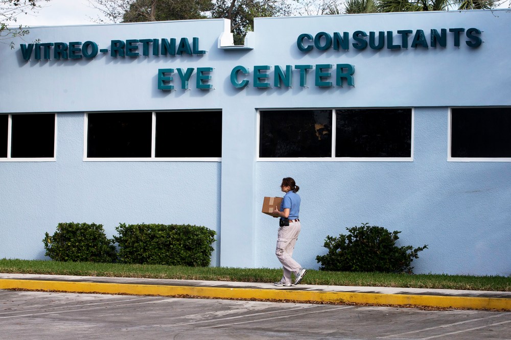 A woman carries a box of equipment into the Vitreo-Rential Consultants Eye Center in West Pam Beach, Fla., Jan. 30 2013.