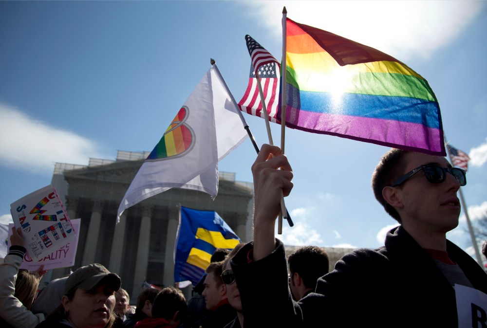 Kevin Coyne of Washington holds flags in front of the Supreme Court in Washington. (Photo by Carolyn Kaster/AP)