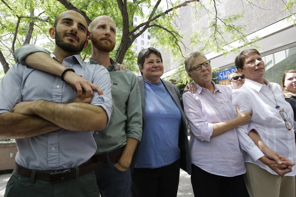 In this June 25, 2014 file photo, from left, plaintiffs Moudi Sbeity and Derek Kitchen, Kate Call, Laurie Wood and Kody Partridge, five of the six people who brought the lawsuit against the Utah's gay marriage ban, stand together at a news conference outs
