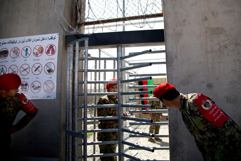 Afghan National Army soldiers peek through the gate of the Parwan Detention Facility in Bagram, Afghanistan, on March 25, 2013.