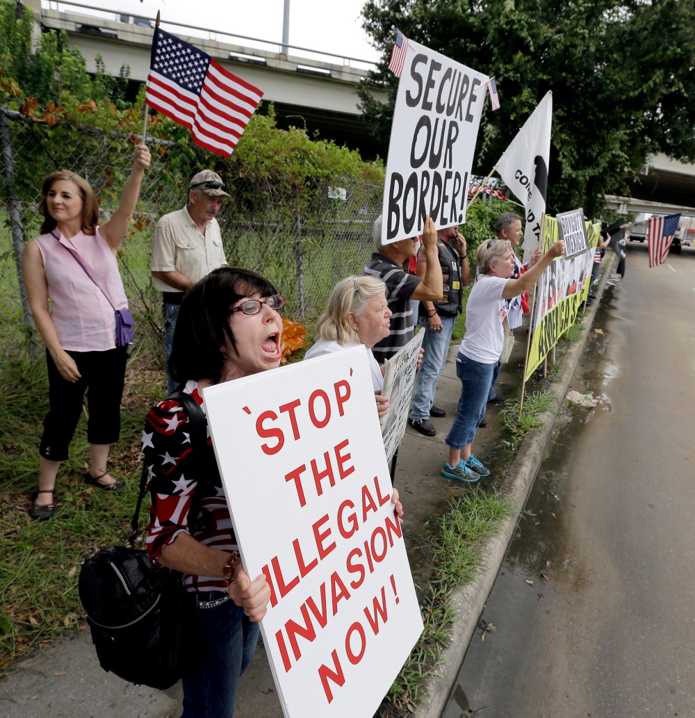 Barbie Miller, left, yells as she joins demonstrators outside the Mexican Consulate Friday, July 18, 2014, in Houston, Texas.