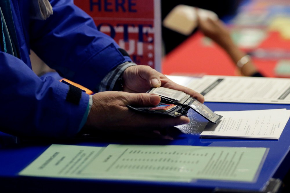 A voter shows his photo identification to an election official at an early voting polling site, in Austin, Texas on Feb. 26, 2014. (Eric Gay/AP)