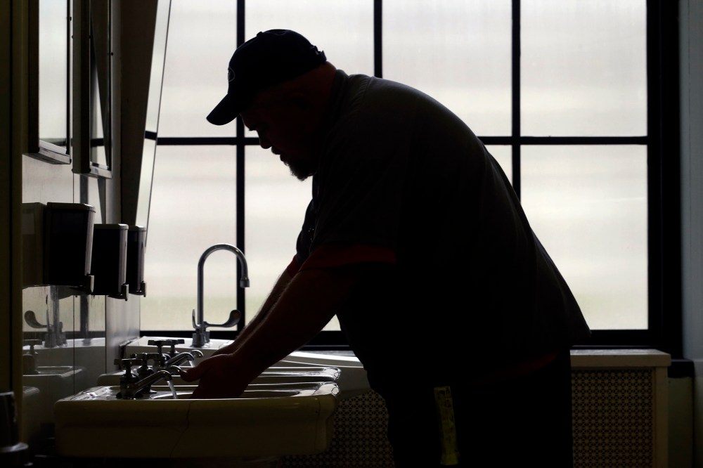 A worker with the West Virginia department of General Services flushes the water as he opens a rest room on the first floor of the State Capitol in Charleston, W.Va., Jan. 13, 2014.