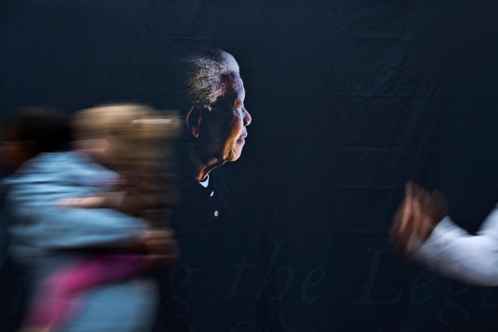 A woman walks past a banner showing former president Nelson Mandela at the Nelson Mandela Centre of Memory in Johannesburg, Dec. 9, 2013.