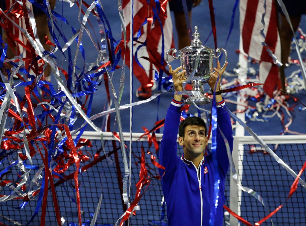 Novak Djokovic, of Serbia, holds up the championship trophy after defeating Roger Federer, of Switzerland, in the men's championship match of the U.S. Open tennis tournament, Sep. 13, 2015, in New York. (Photo by Seth Wenig/AP)