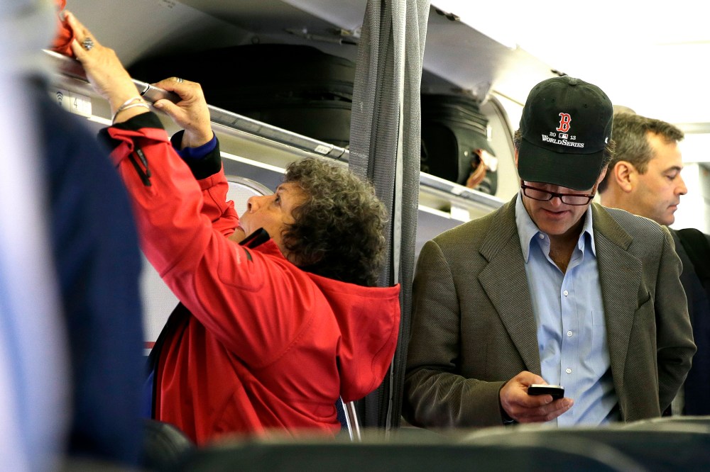 In this  Oct. 31, 2013 file photo, a passenger checks his cell phone while boarding a flight, in Boston.