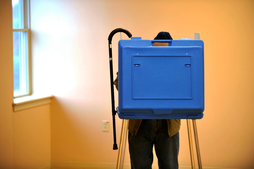 Ninety-one-year-old Dave Silverman hangs his cane on the booth while voting in State College, Pa., Nov. 5, 2013.