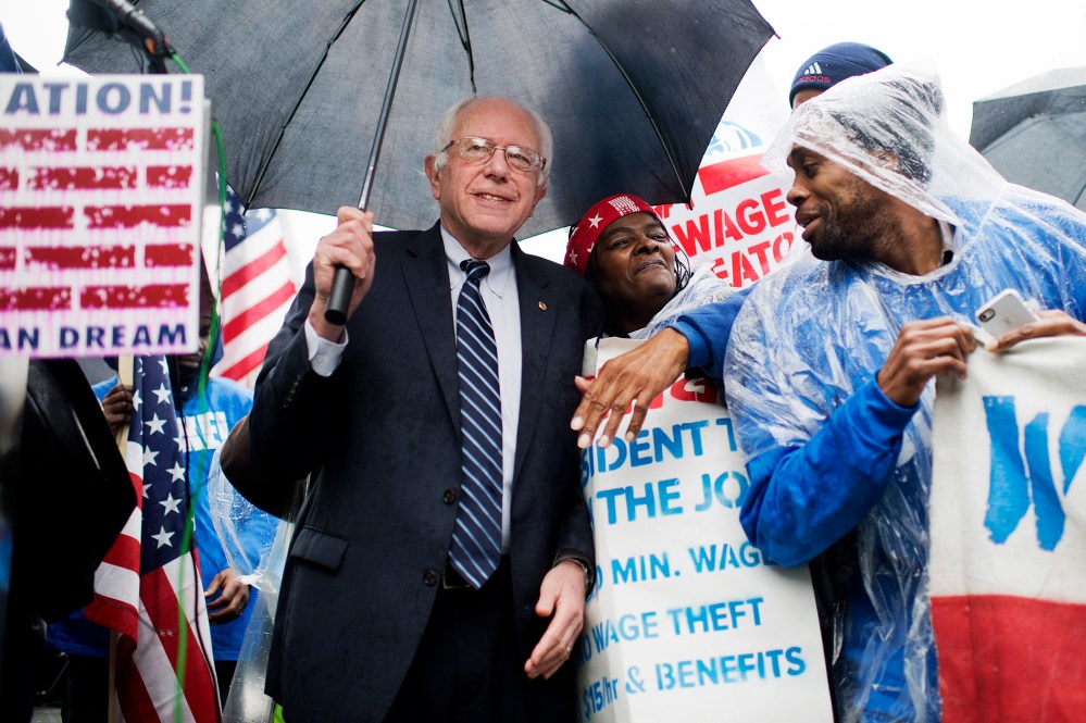 On the day of a Republican presidential debate, Sen. Bernie Sanders, I-Vt., attends a rally in Upper Senate Park with striking workers to call for a minimum wage of $15 per hour, Nov. 10, 2015. (Photo By Tom Williams/CQ Roll Call/AP)