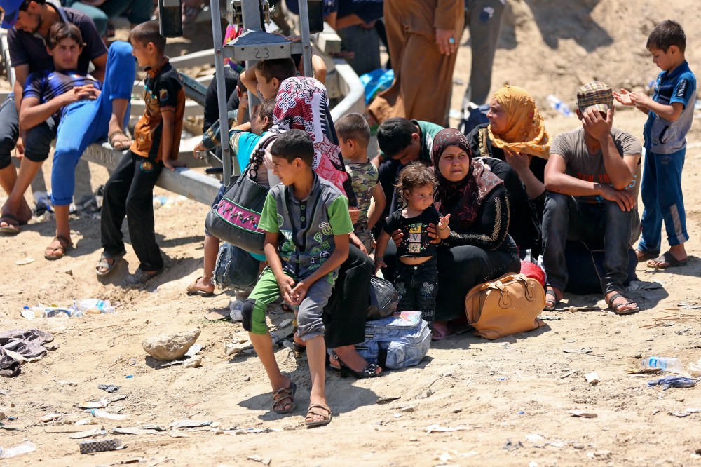 Displaced Iraqis from Ramadi rest before crossing the Bzebiz bridge after spending the night walking towards Baghdad, as they flee their hometown on May 16, 2015. (Photo by Hadi Mizban/AP)