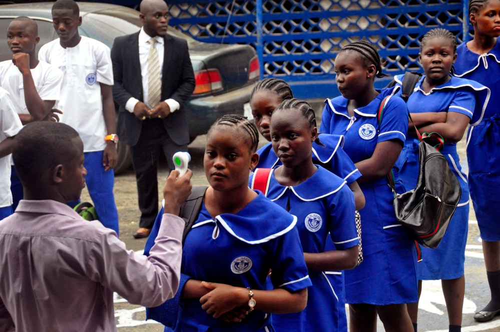 A Liberian school teacher takes the temperature of students as they arrive for morning lessons at school, as part of the Ebola prevention measures put in place at the BW Harris High School in Monrovia, Liberia, Feb. 16, 2015. (Photo by Abbas Dulleh/AP)
