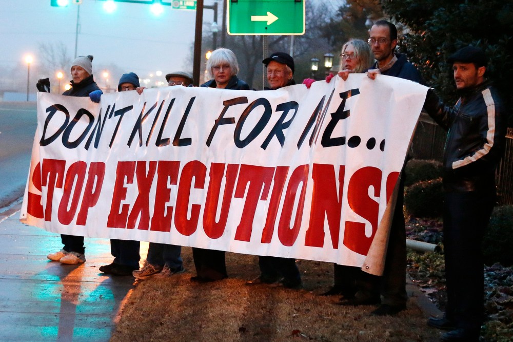 Death penalty opponents hold a sign outside the Governor's mansion in Oklahoma City, Jan. 9, 2014.