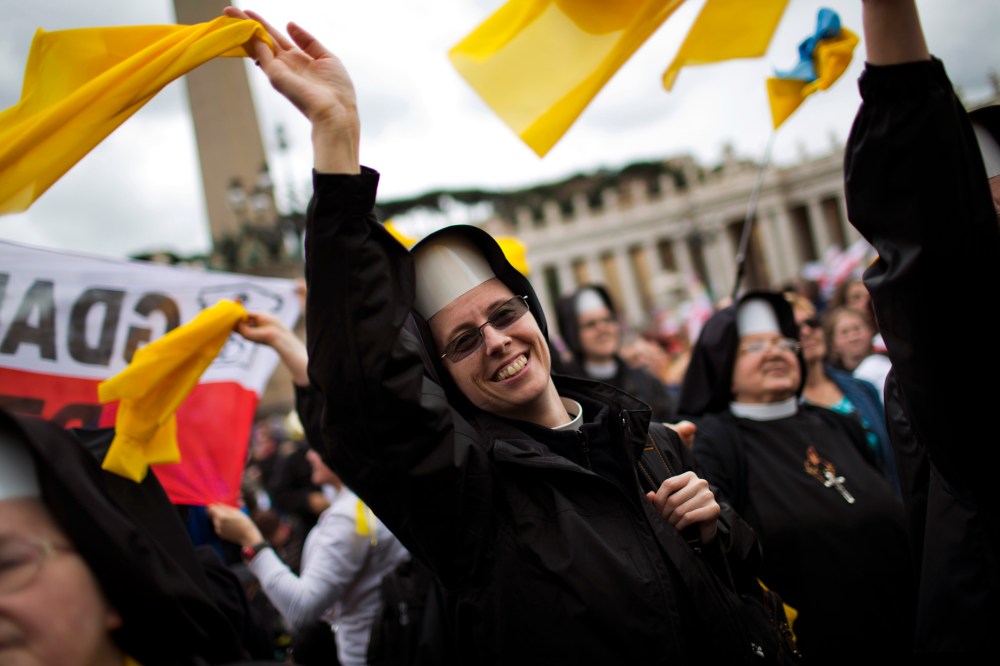 Nuns wave as Pope Francis is driven through the crowd after presiding over a solemn ceremony in St. Peter's Square at the Vatican, Sunday, April 27, 2014.