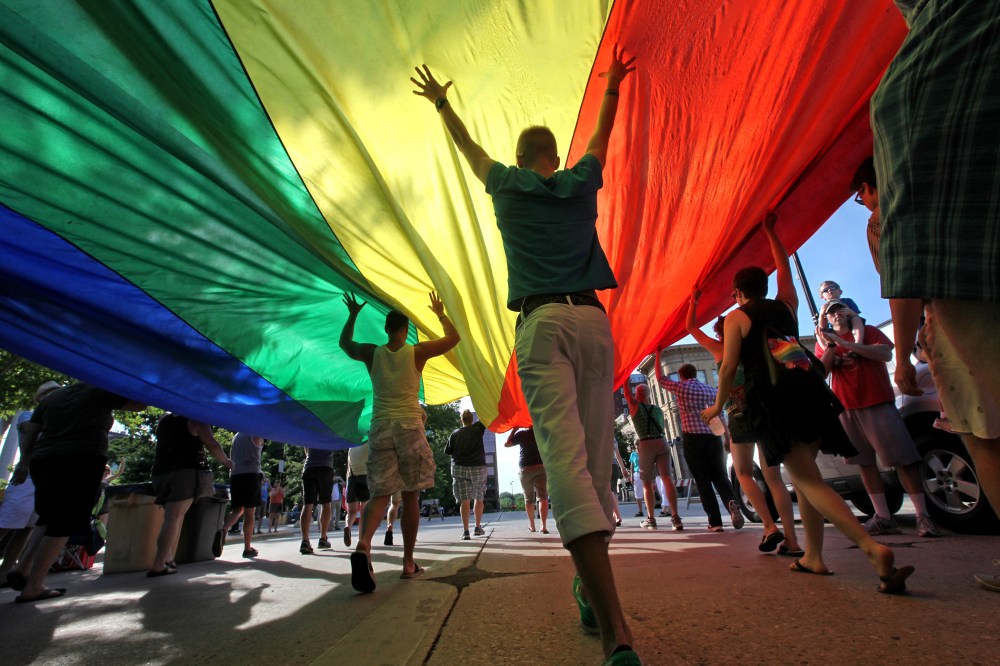 Supporters of a U.S. Supreme Court ruling which overturns the federal Defense of Marriage Act (DOMA) carry a large rainbow flag during a parade around the Wisconsin State Capitol in Madison, Wis. Wednesday, June 26, 2013.