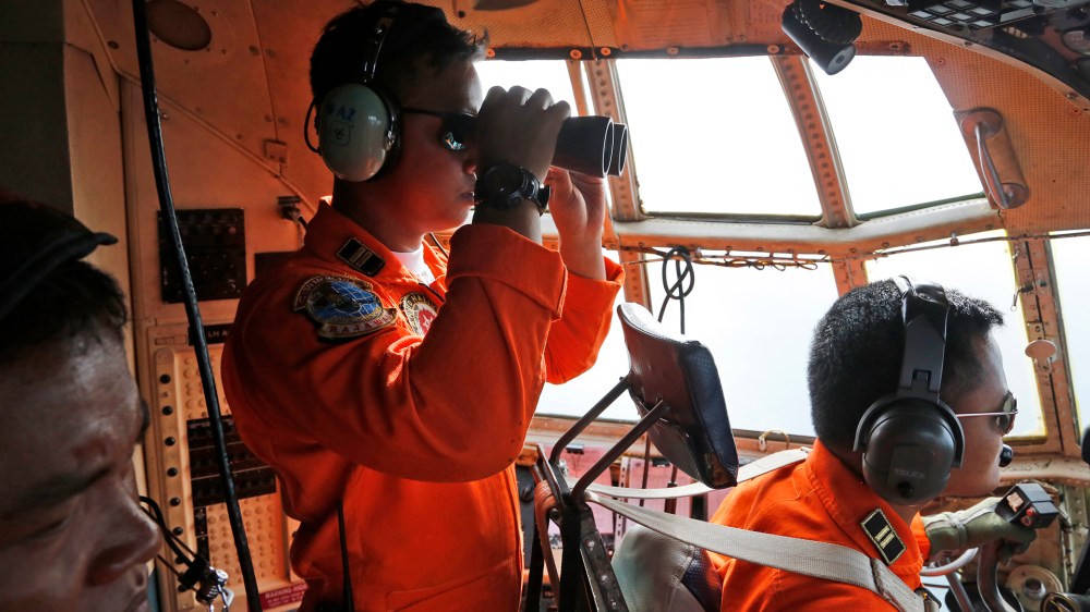 The crew of the Indonesian Air Force uses binoculars to scan the horizon during a search operation for the missing AirAsia flight 8501 jetliner on Dec. 29, 2014. (Dita Alangkara/AP)