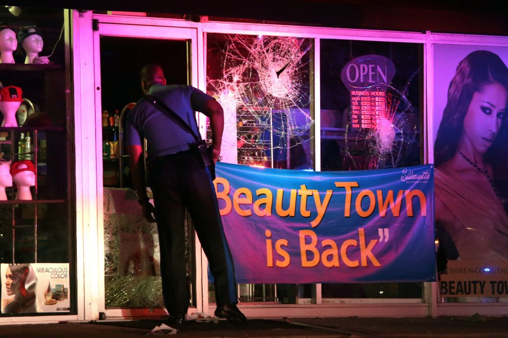 A Missouri Highway Patrol trooper looks inside the vandalized Beauty Town store on West Florissant Avenue in Ferguson late Tuesday, Sept. 23, 2014.