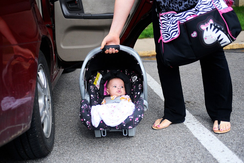 18 year-old mother Kasiyah Buckner lifts her daughter into her car outside of St. Paul Lutheran in St. Joseph, Mo., May 9, 2013.