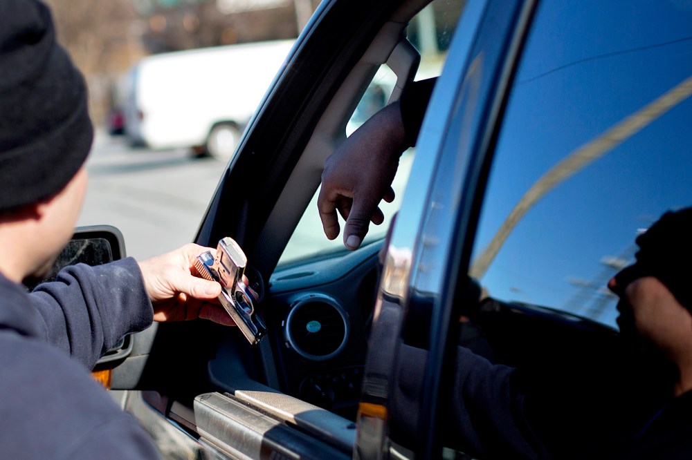 A police officer collects a gun from from a motorist during a gun buyback, in Atlanta, Georgia, Jan. 16, 2014.