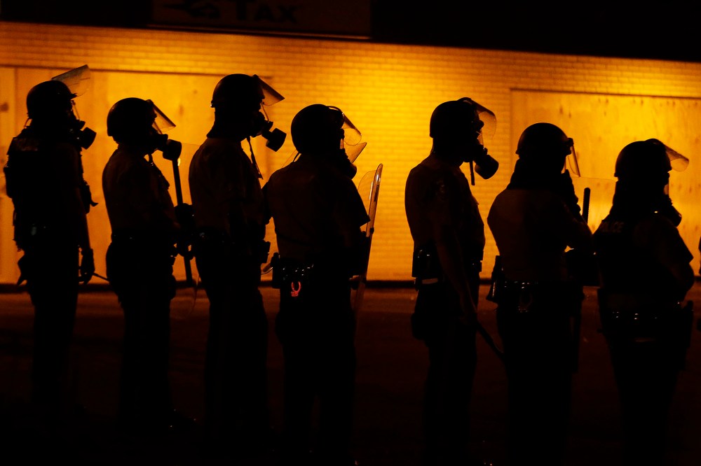 Police wait to advance after tear gas was used to disperse a crowd, Aug. 17, 2014, in Ferguson, Mo.