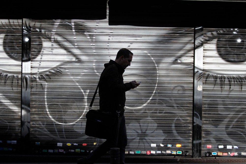 A man looks at his cell phone as he walks on the street in downtown Madrid, Oct. 31, 2013.