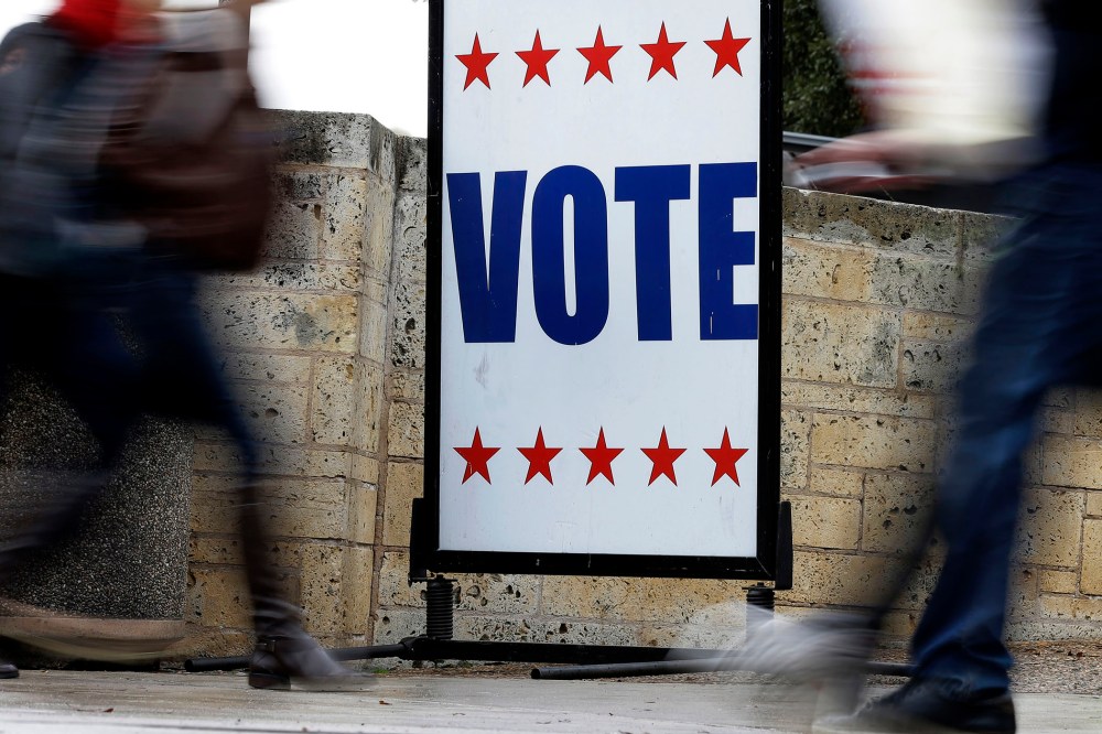 Pedestrians pass voting signs near an early voting polling site, in Austin, Texas.